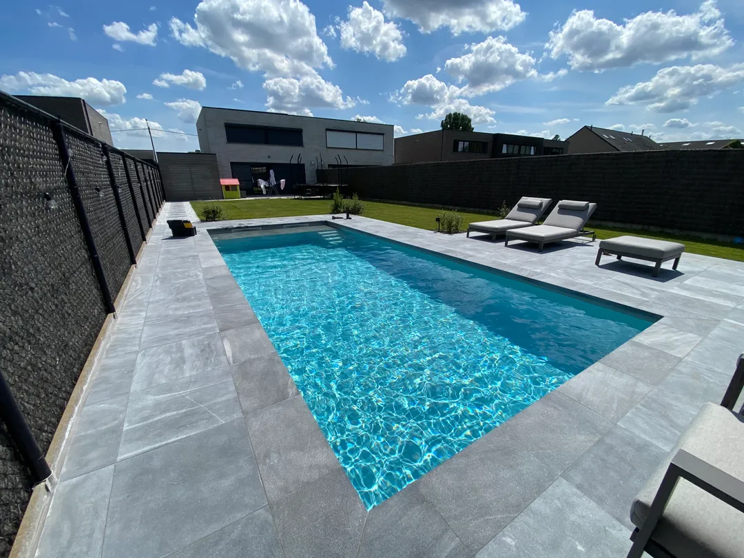 Modern zwembad met strakke blauwe liner en grijze terrasrand na renovatie door Liner Plaatsen