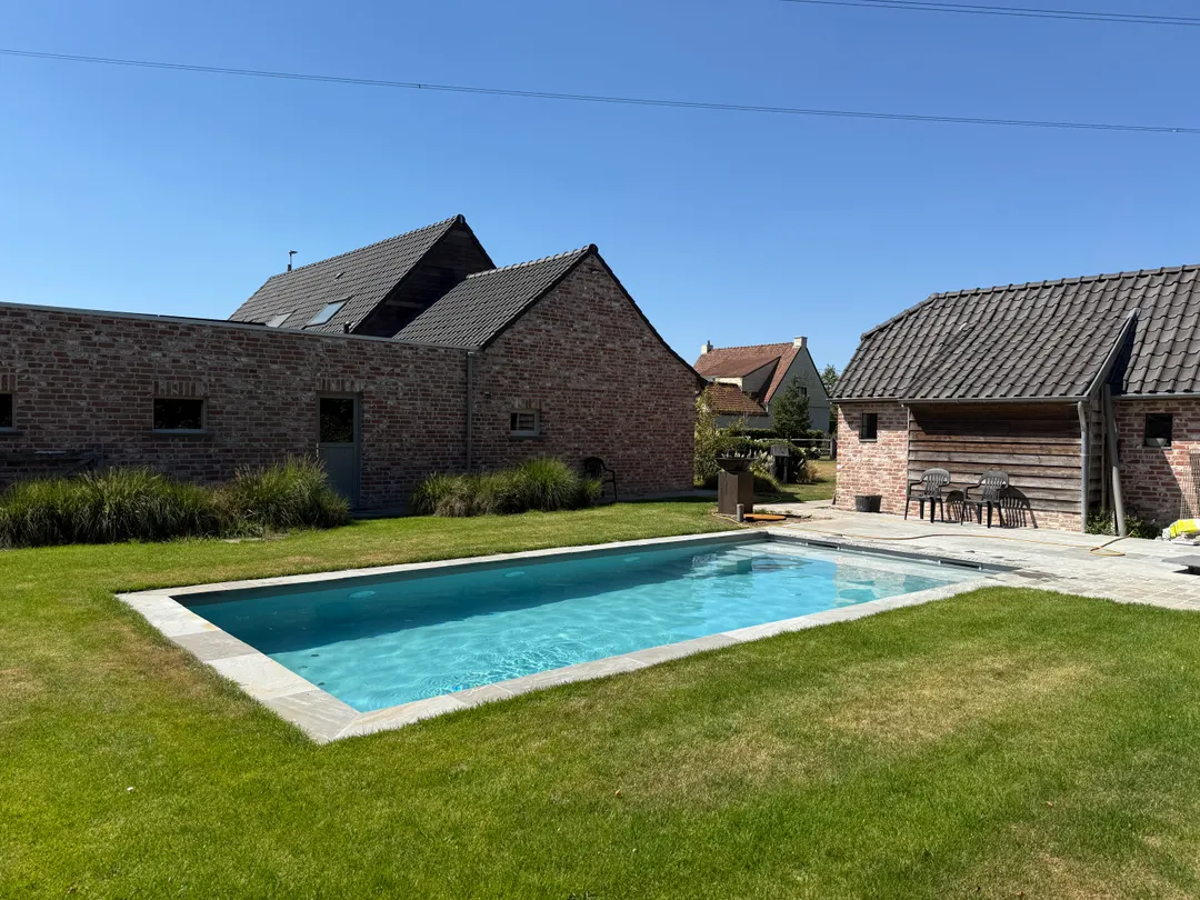 Strak geplaatste zwembadliner in een modern gerenoveerd zwembad in een groene tuin