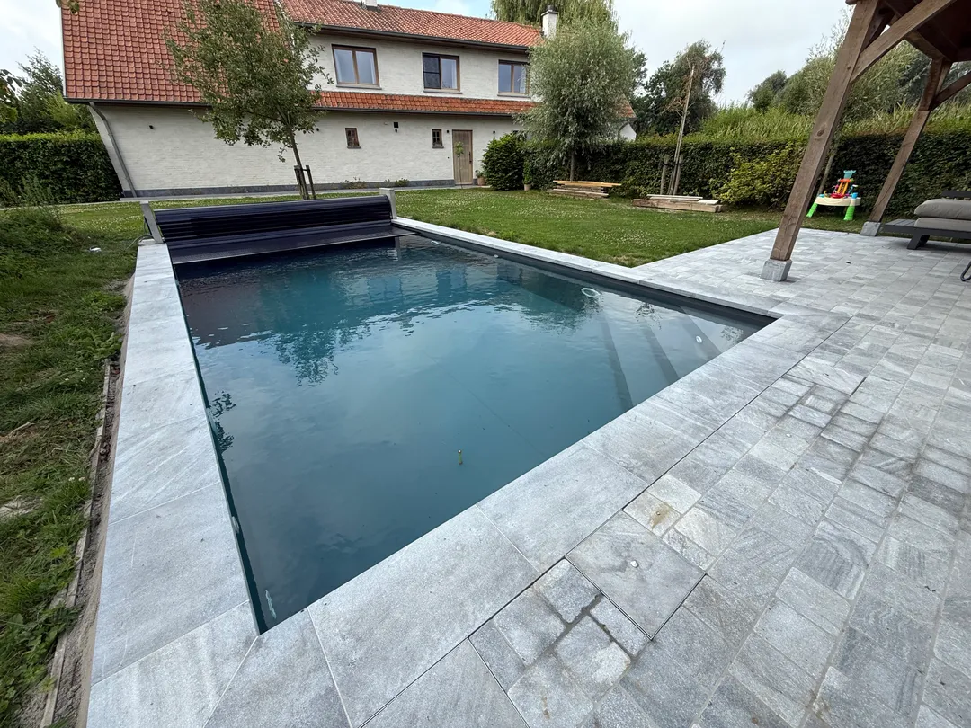 Strakke donkere zwembadliner met automatische afdekking en moderne grijze terrastegels door Liner Plaatsen