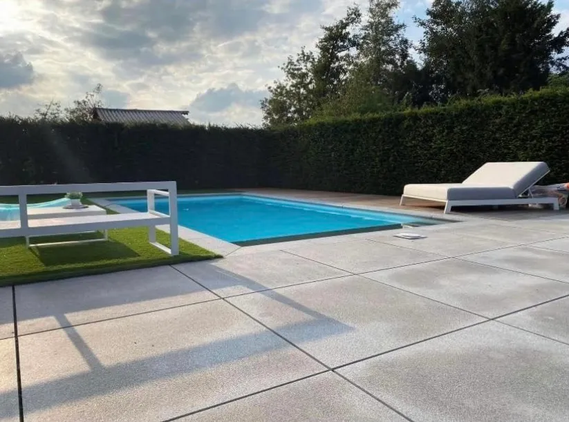 Modern zwembad met strakke blauwe liner en lichte tegels na professionele zwembadrenovatie