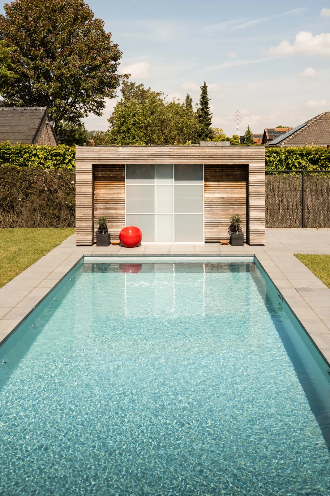 Lang zwembad met turquoise water en houten poolhouse in Wevelgem — afgewerkte zwembadliner door Liner Plaatsen