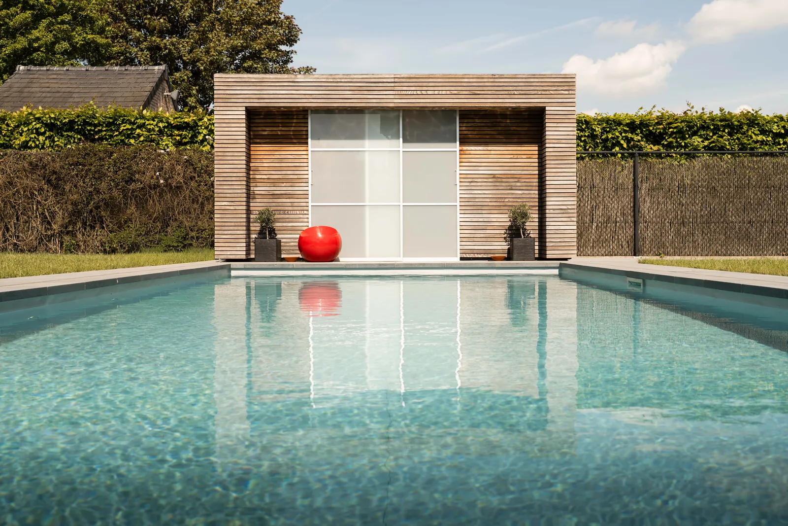 Modern zwembad met turquoise water en donkergrijze zwembadliner bij een houten poolhouse in Wevelgem — afgewerkt project door Liner Plaatsen
