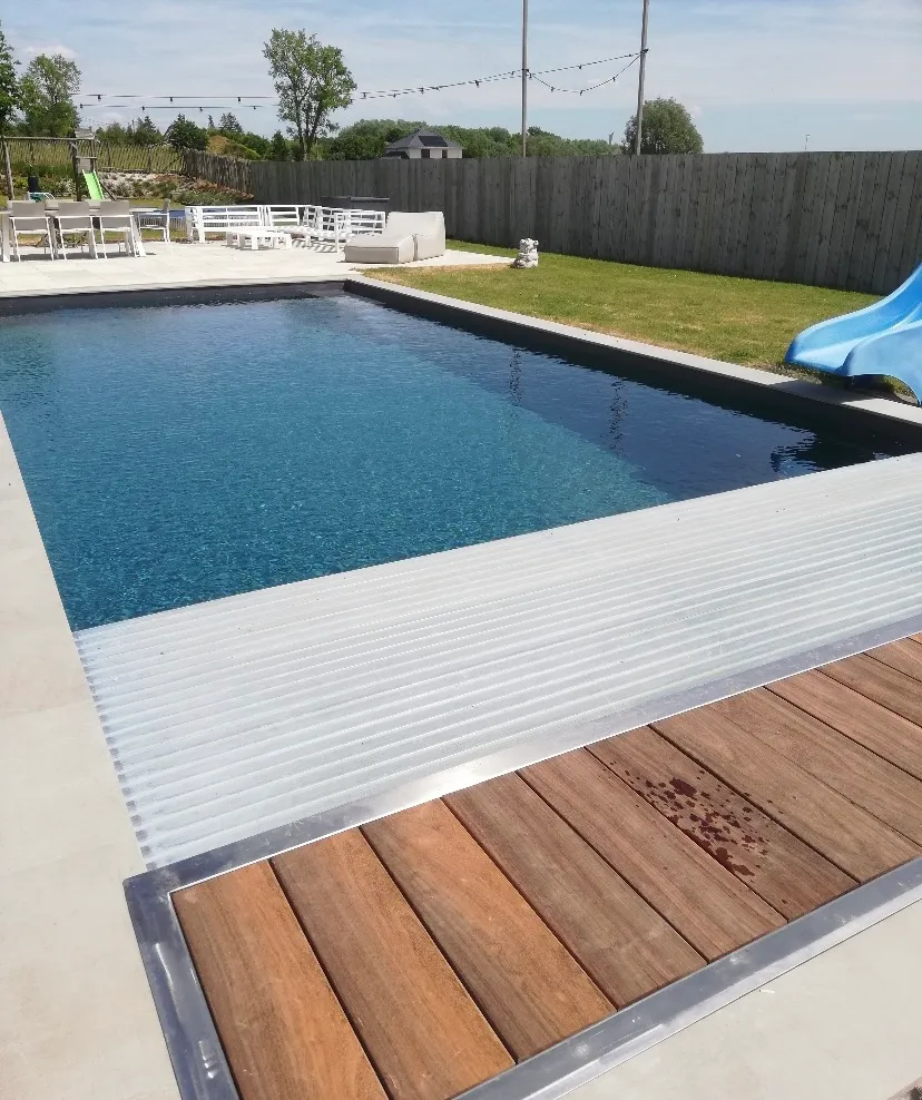 Strak afgewerkt zwembad met grijze liner en een automatisch zwembadrolluik na een professionele renovatie